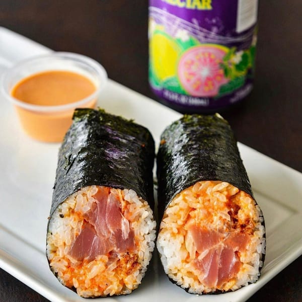 Two Tiger Plate poke hand rolls with tuna, rice, and spicy sauce, with a side of sauce and a drink.