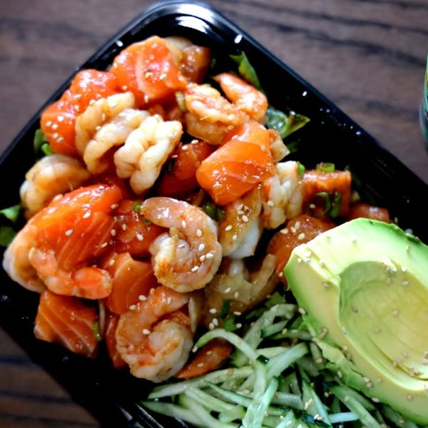 Tiger Plate poke bowl with salmon, shrimp, avocado, and cucumber, sprinkled with sesame seeds.
